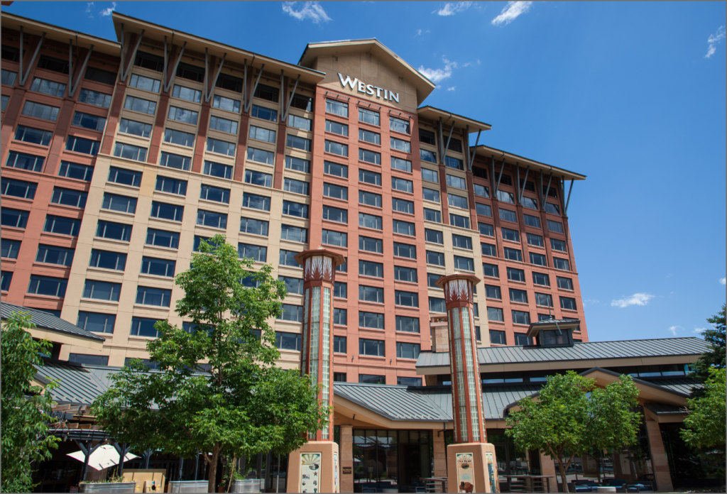 The outside of the Westin Hotel. It is a light red and tan building.